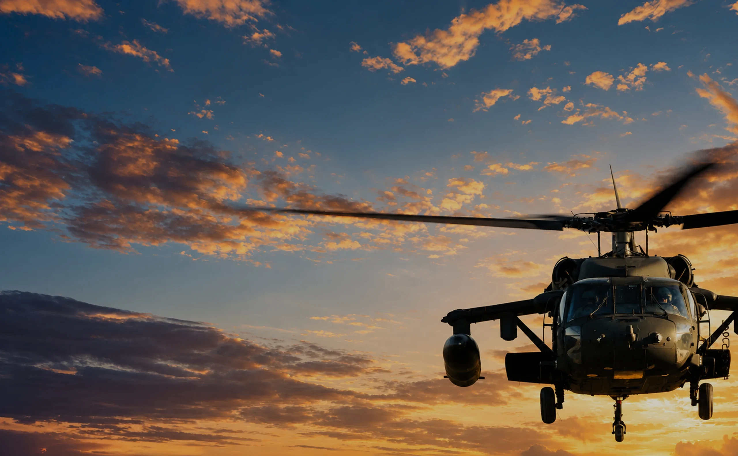 Military helicopter flying beneath a dramatic sunset sky